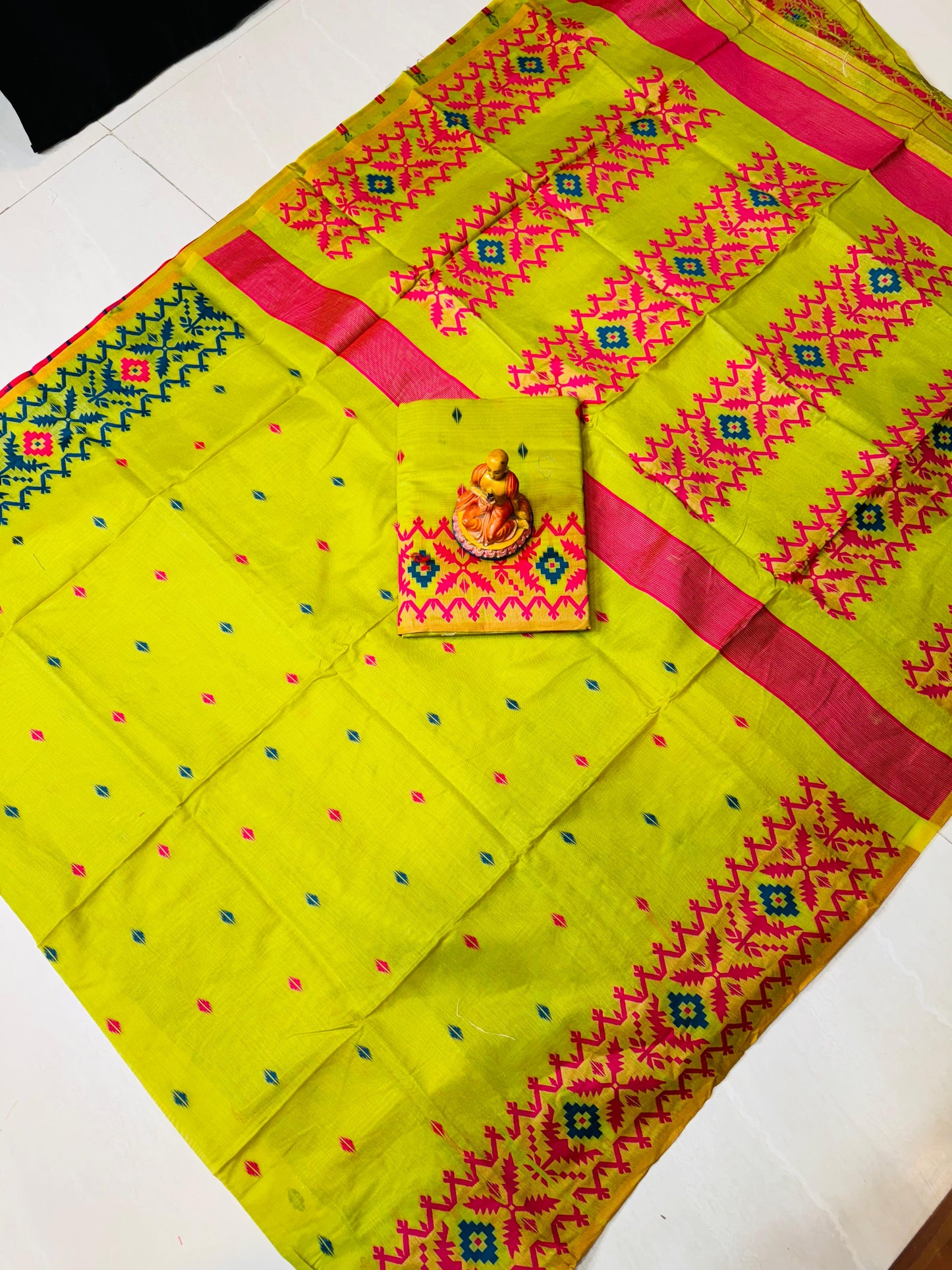Yellow saree with pink and green patterns on a white background