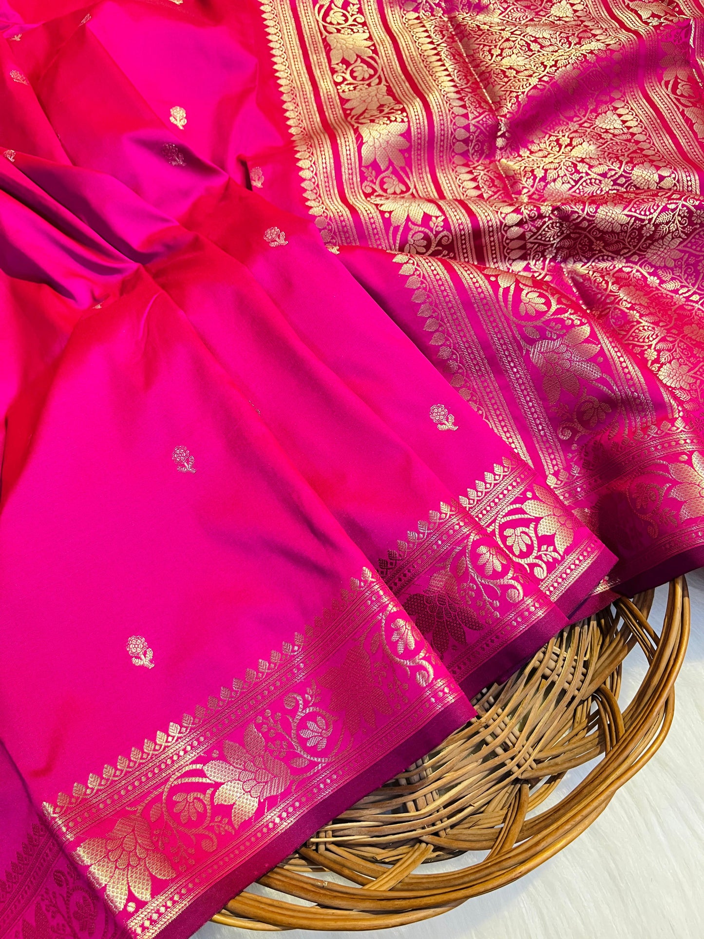 Pink saree with gold patterns on a woven basket