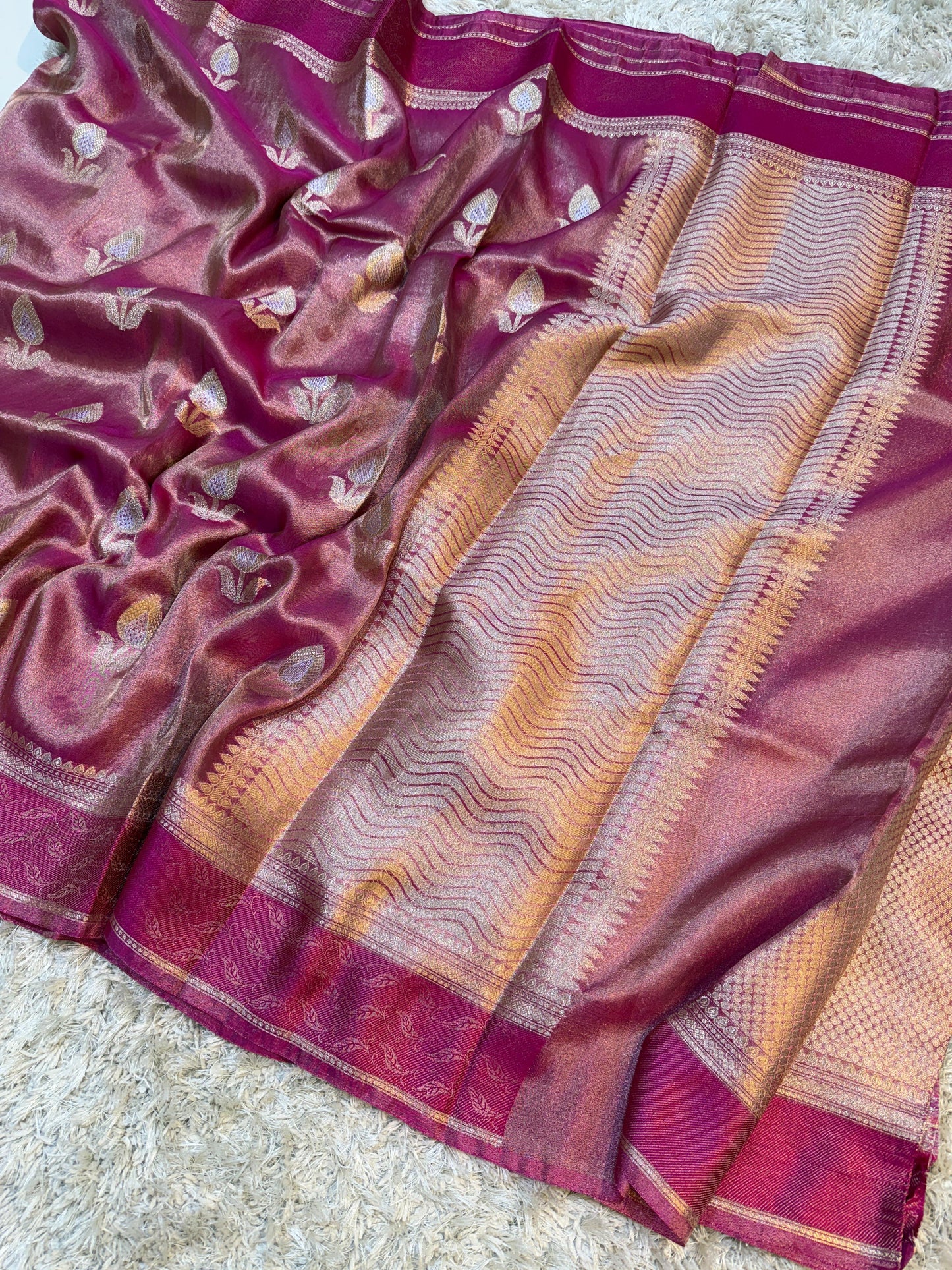 Close-up of a pink and gold saree with intricate patterns on a light background