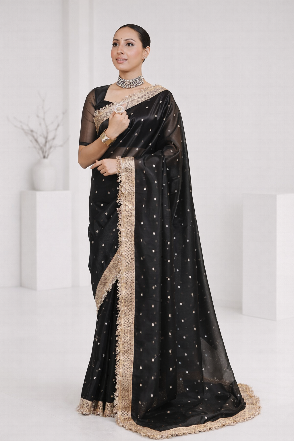 Woman wearing a black saree with gold border on a white background