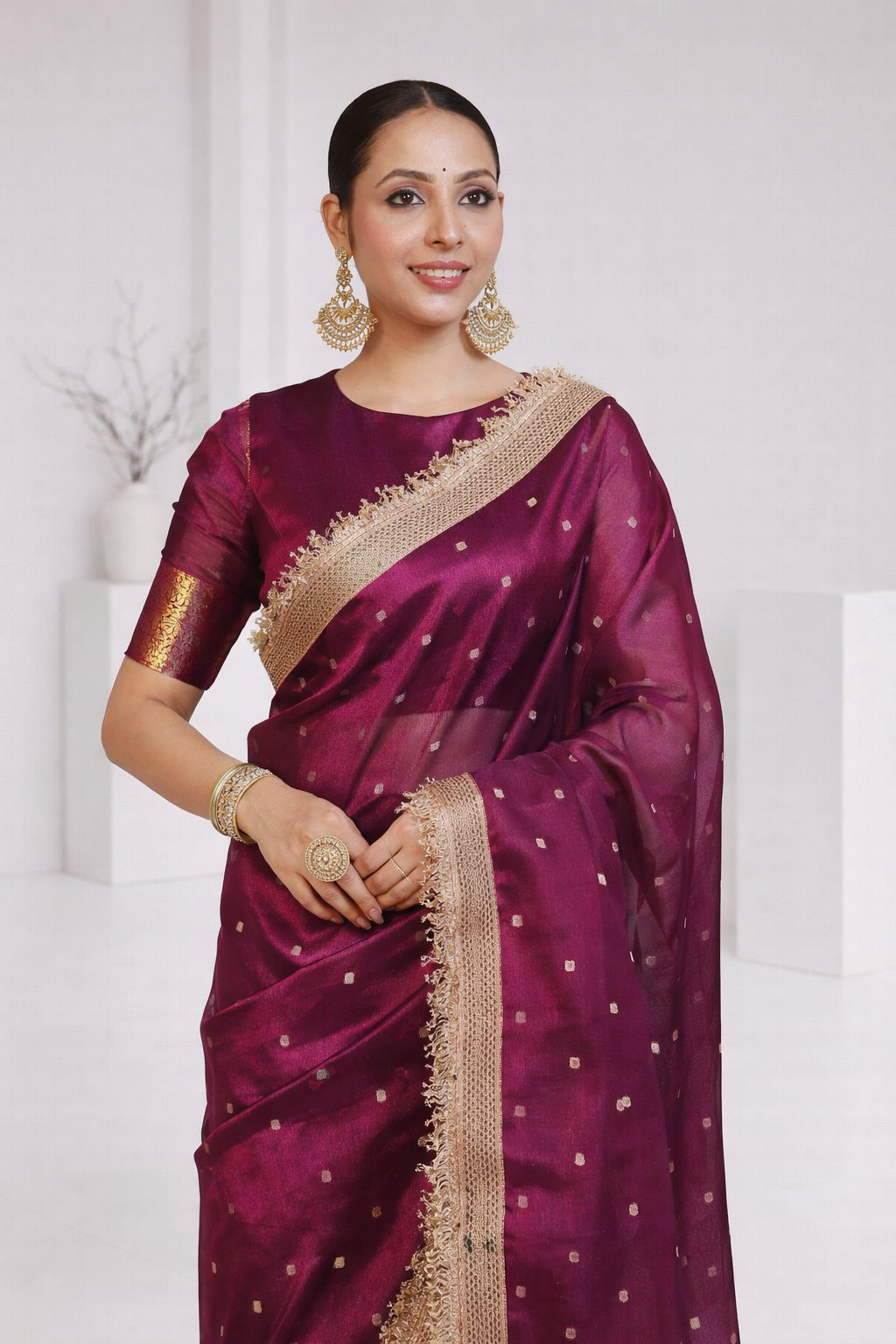 Woman wearing a maroon saree with gold border on a white background