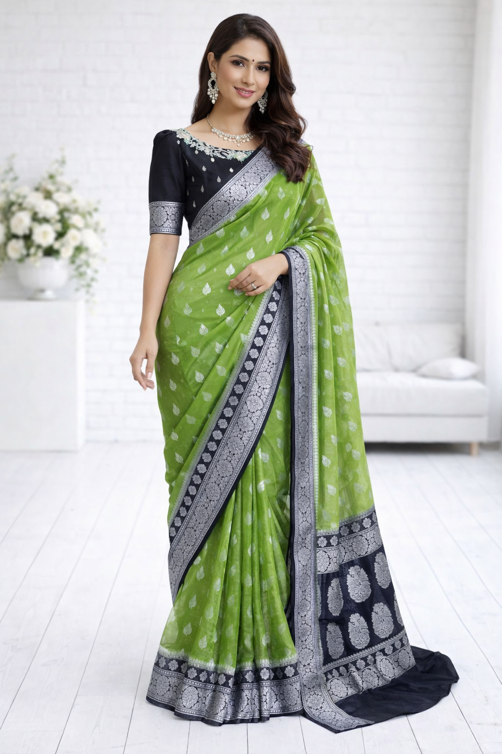 Woman wearing a green and black saree with a white background