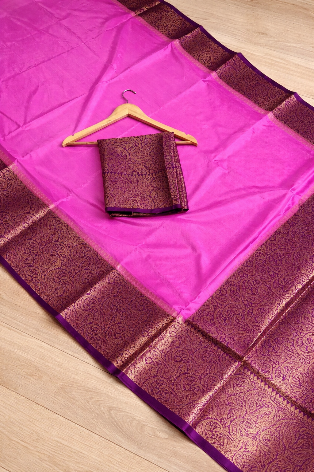 Purple and pink saree with a hanger on a wooden floor