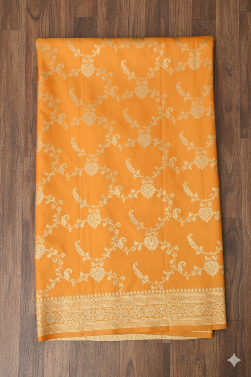 Mustard yellow saree with white floral patterns on a wooden surface