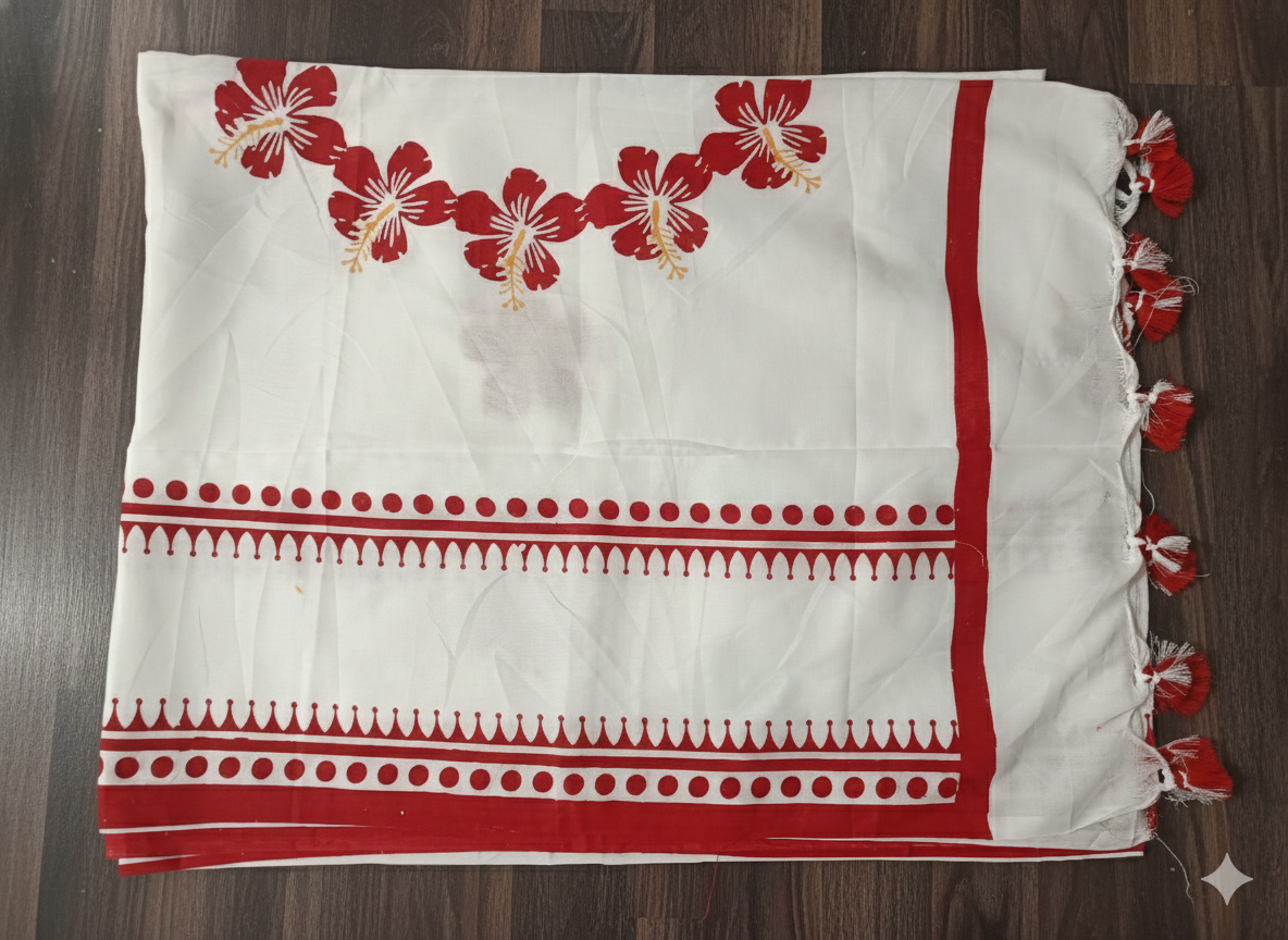 White fabric with red floral embroidery and decorative trim on a wooden surface