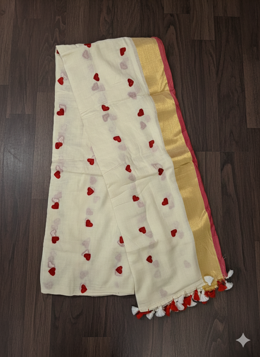 White saree with red heart patterns and gold border on a wooden surface