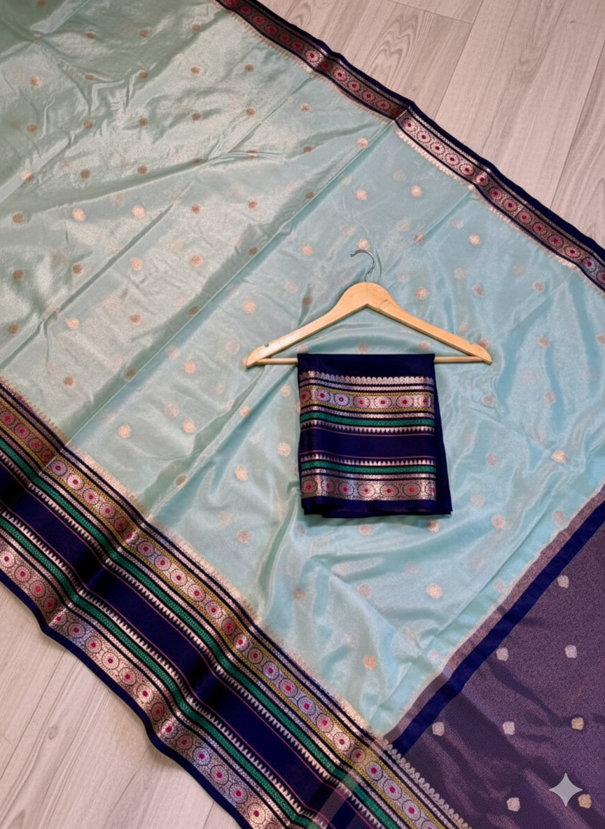 Light blue saree with dark blue border and pattern on a wooden floor