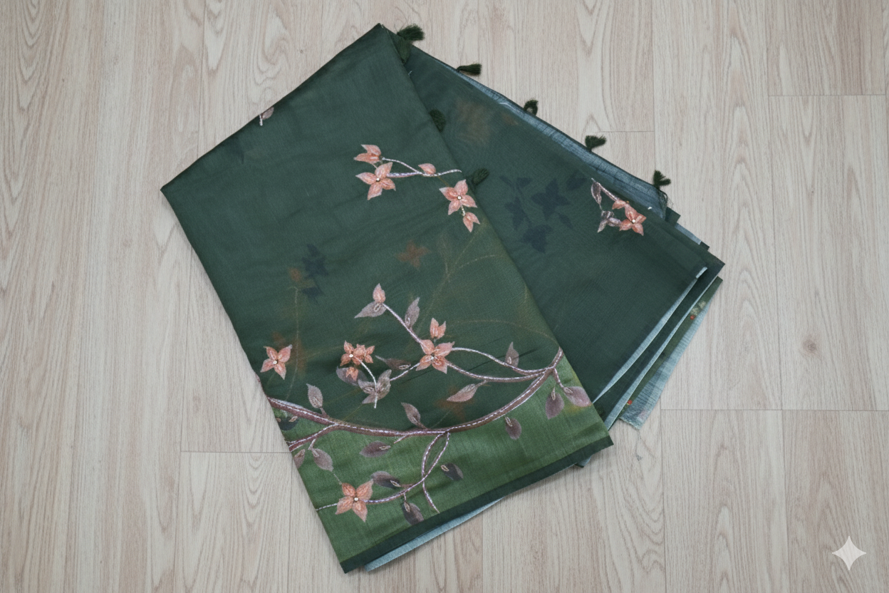Green fabric with floral embroidery on a light wooden floor