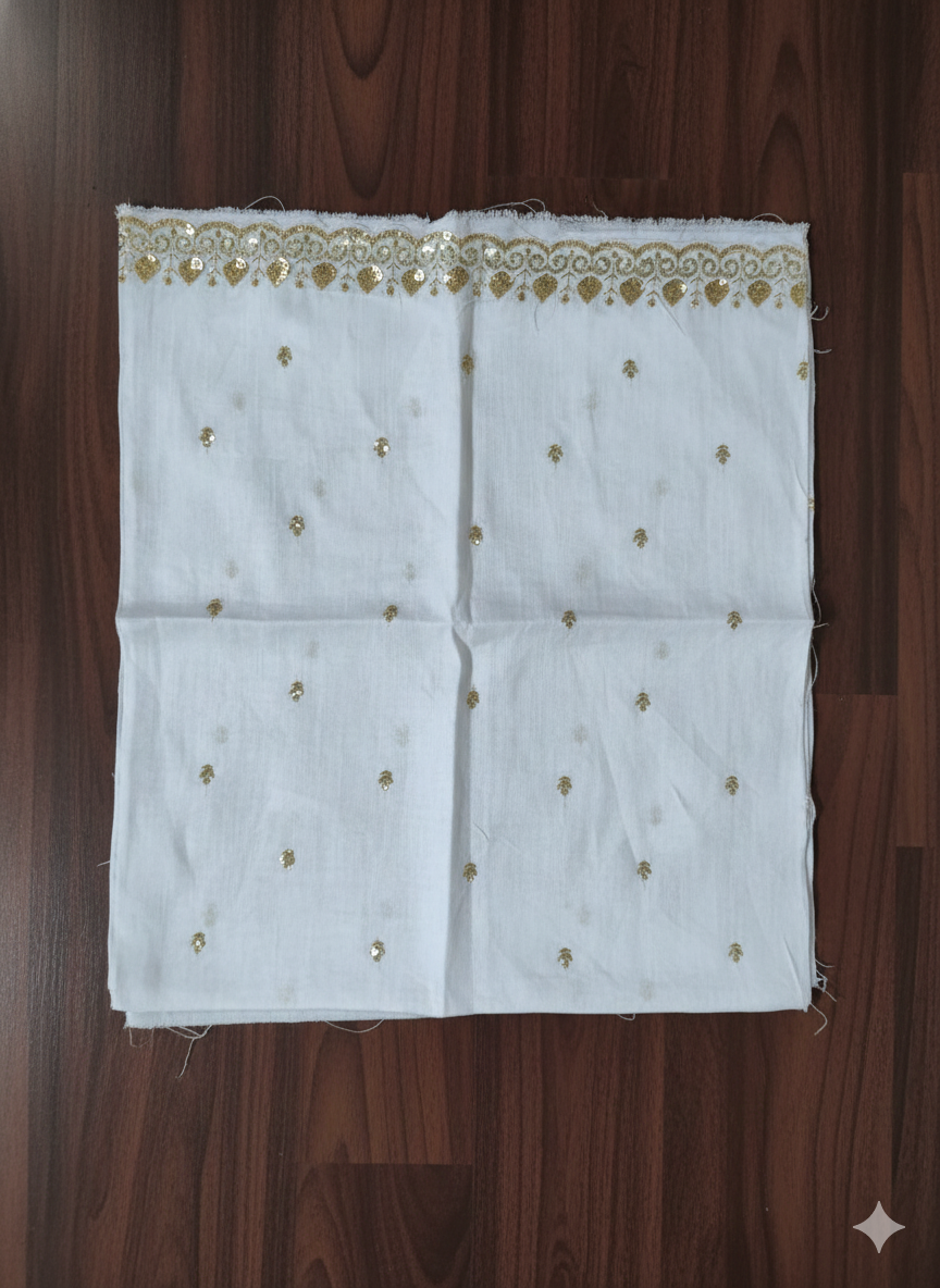 White fabric with gold embroidery on a wooden surface