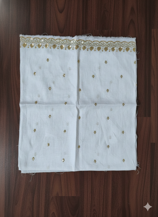 White fabric with gold embroidery on a wooden surface