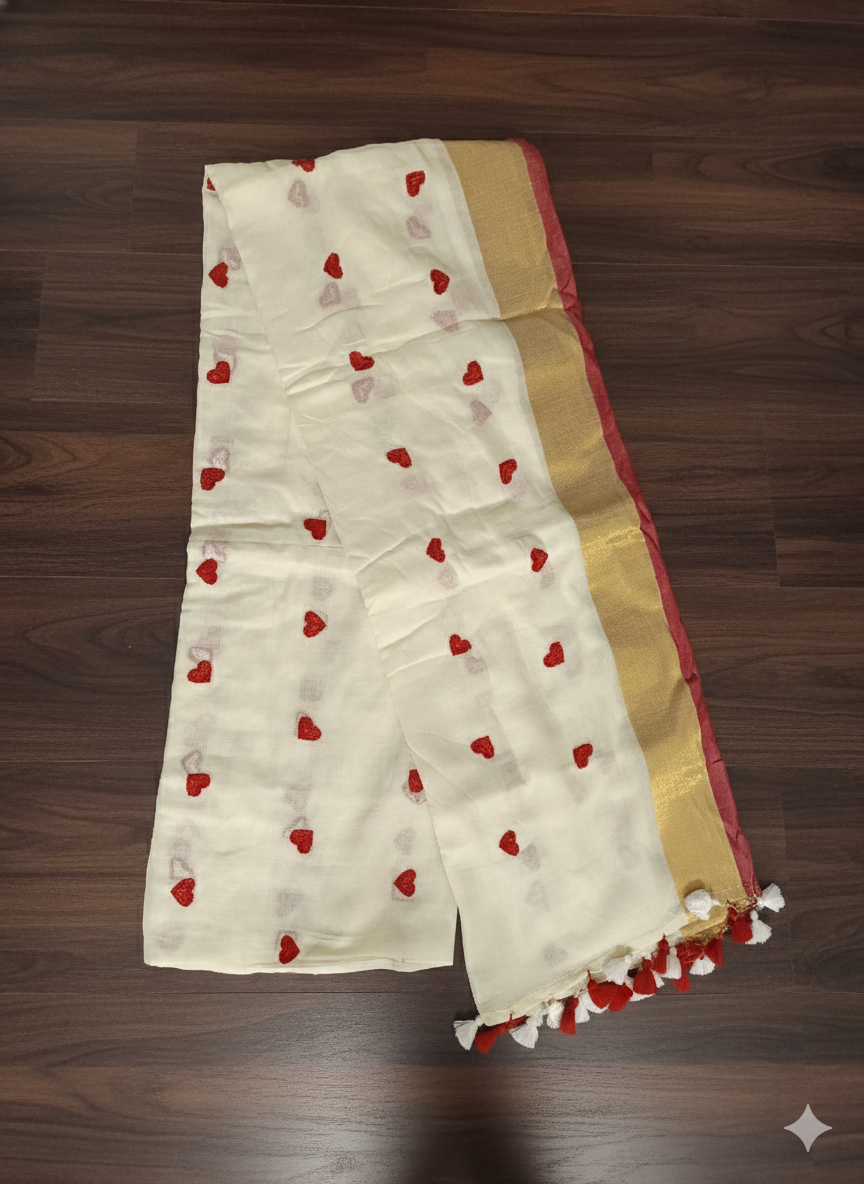 White saree with red heart patterns and gold border on a wooden surface