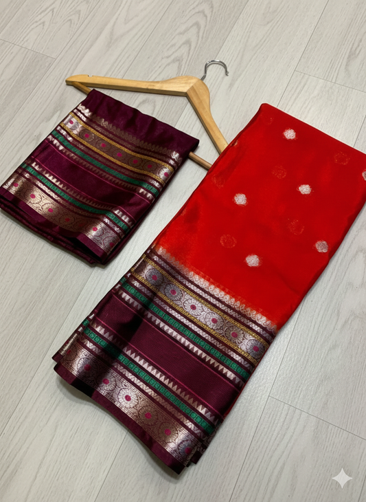 Red and maroon saree with gold border on a wooden hanger against a light wooden floor.
