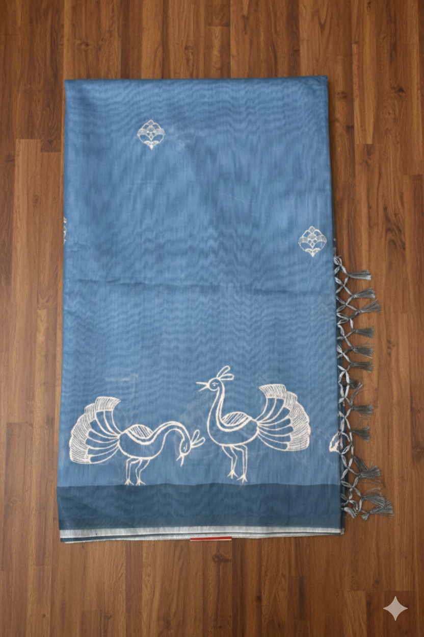 Blue towel with white bird designs and tassels on a wooden surface