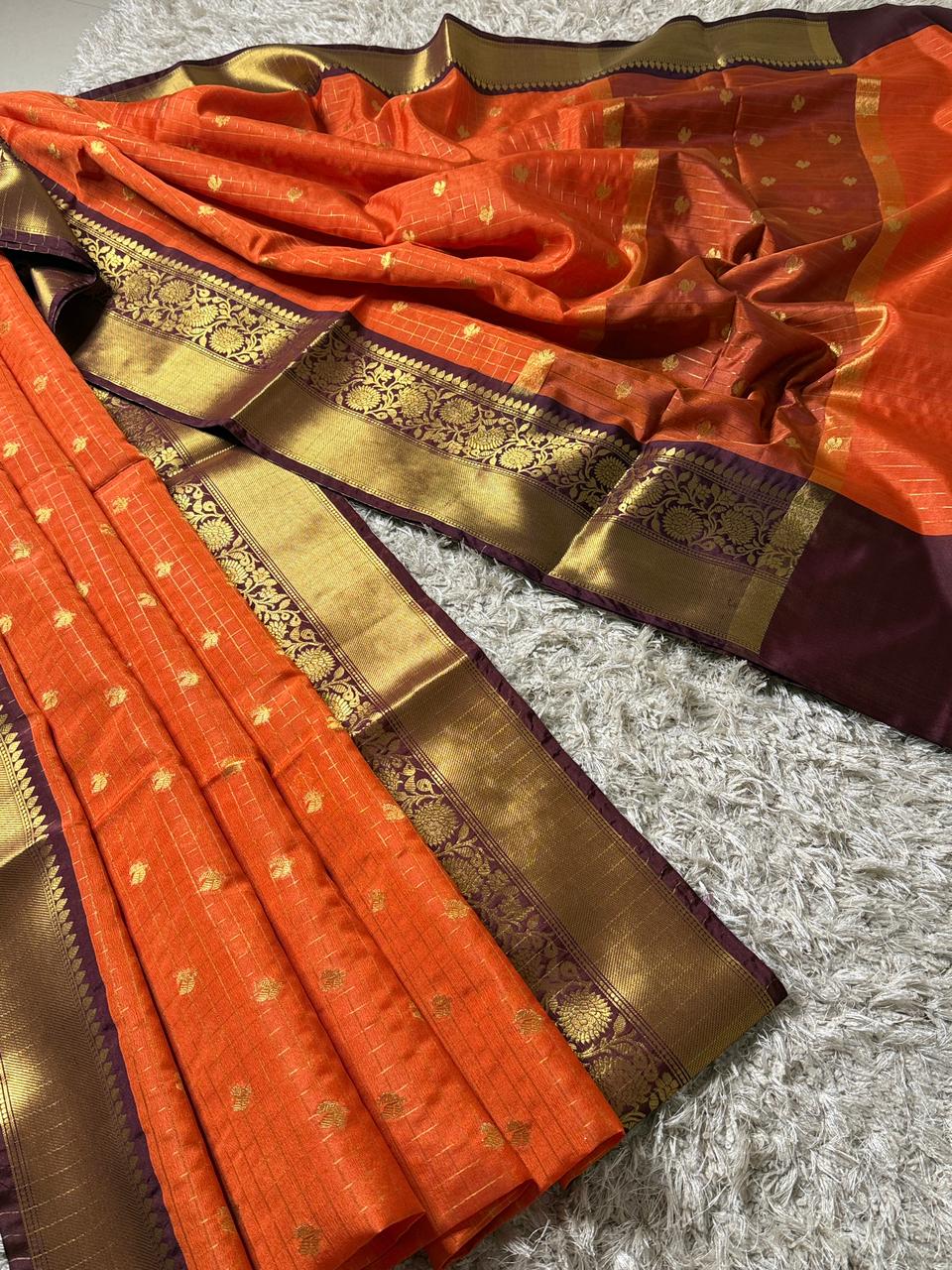Orange saree with gold and purple border on a textured surface