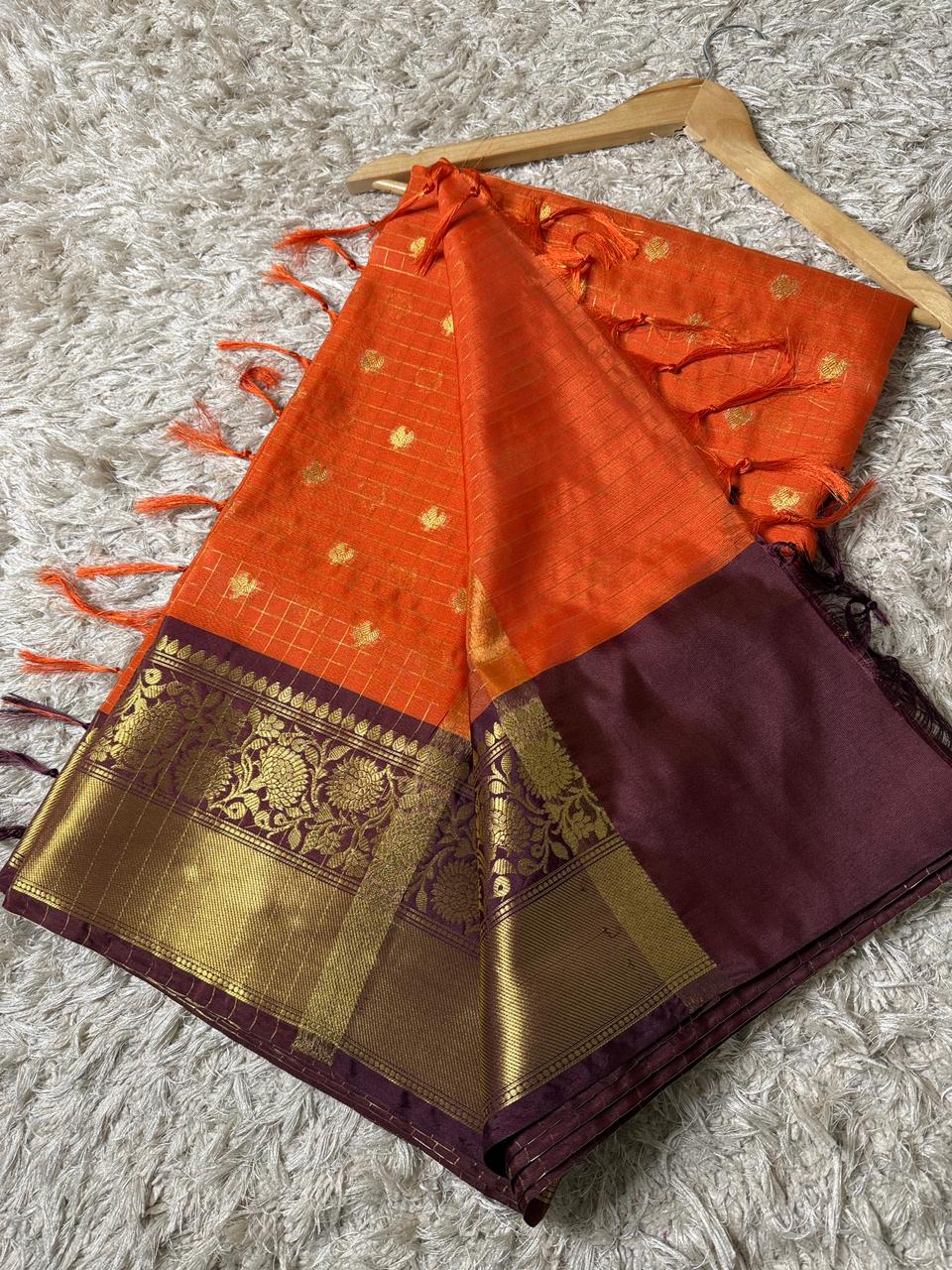 Orange and purple saree with gold patterns on a textured surface