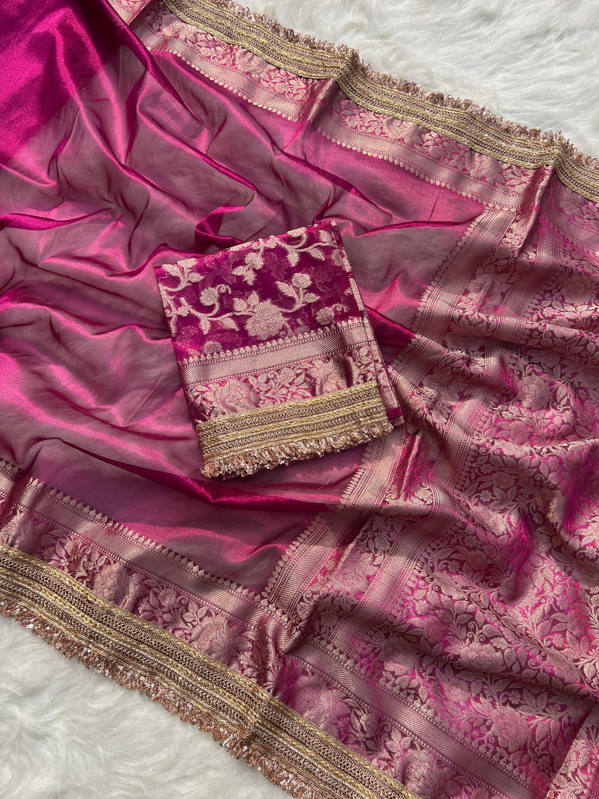 Pink saree with gold border and matching pouch on a white background