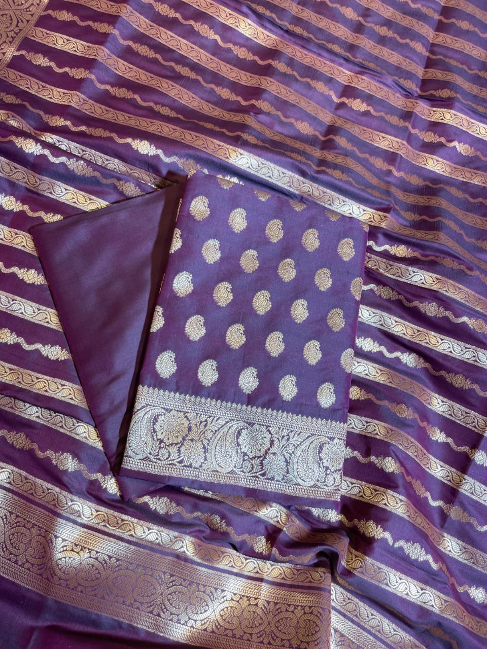Purple fabric with gold patterns and a folded section on a matching background