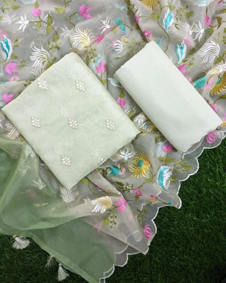 Light green fabric with floral embroidery on a floral-patterned fabric background