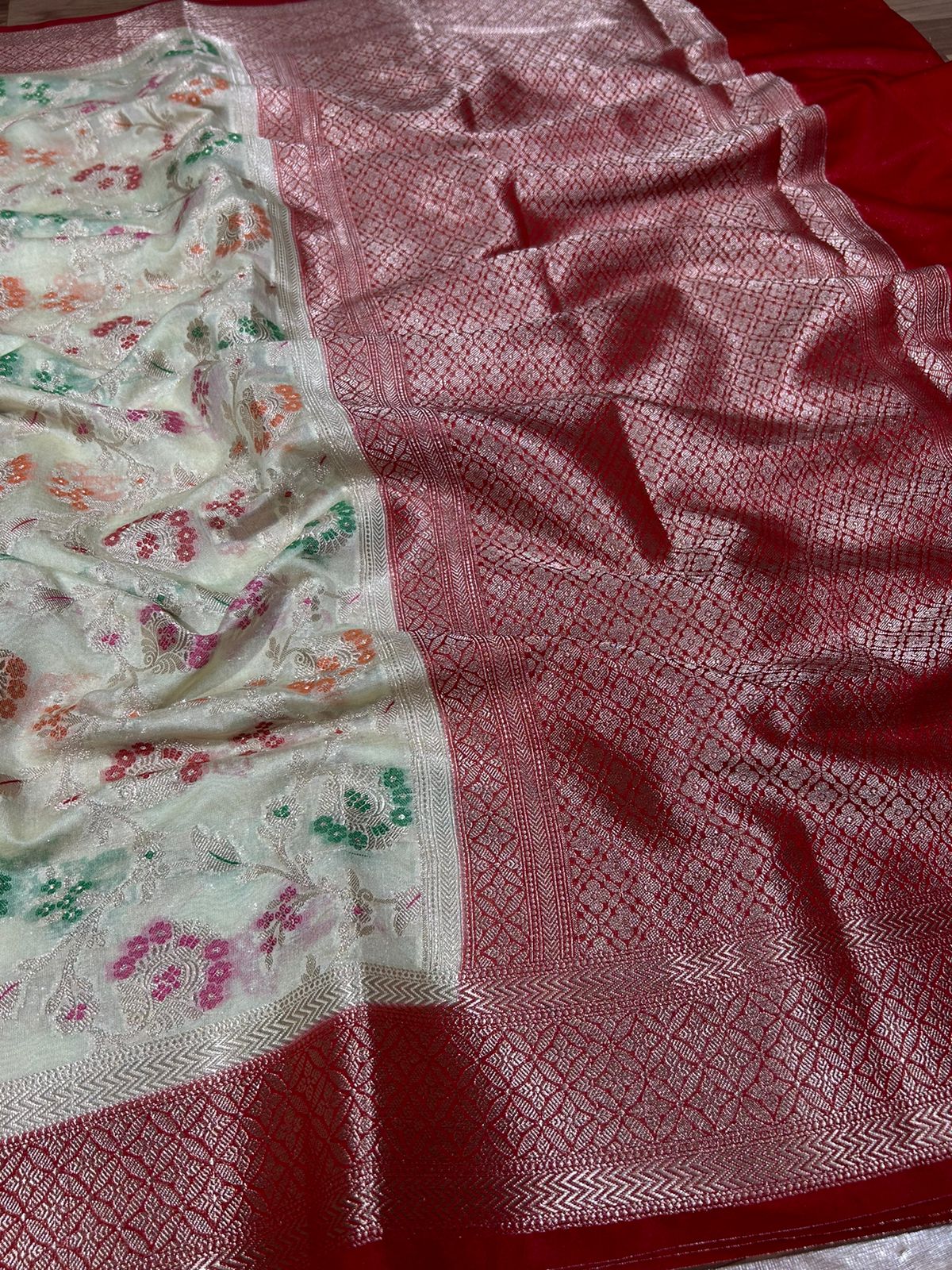 Two pieces of fabric with different patterns, one white with floral designs and the other red with a geometric pattern.