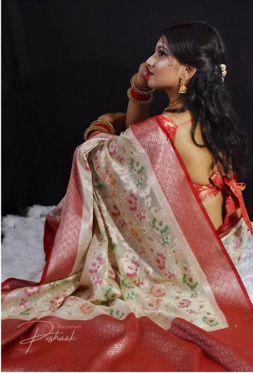 Woman in a red and white saree with floral patterns against a dark background