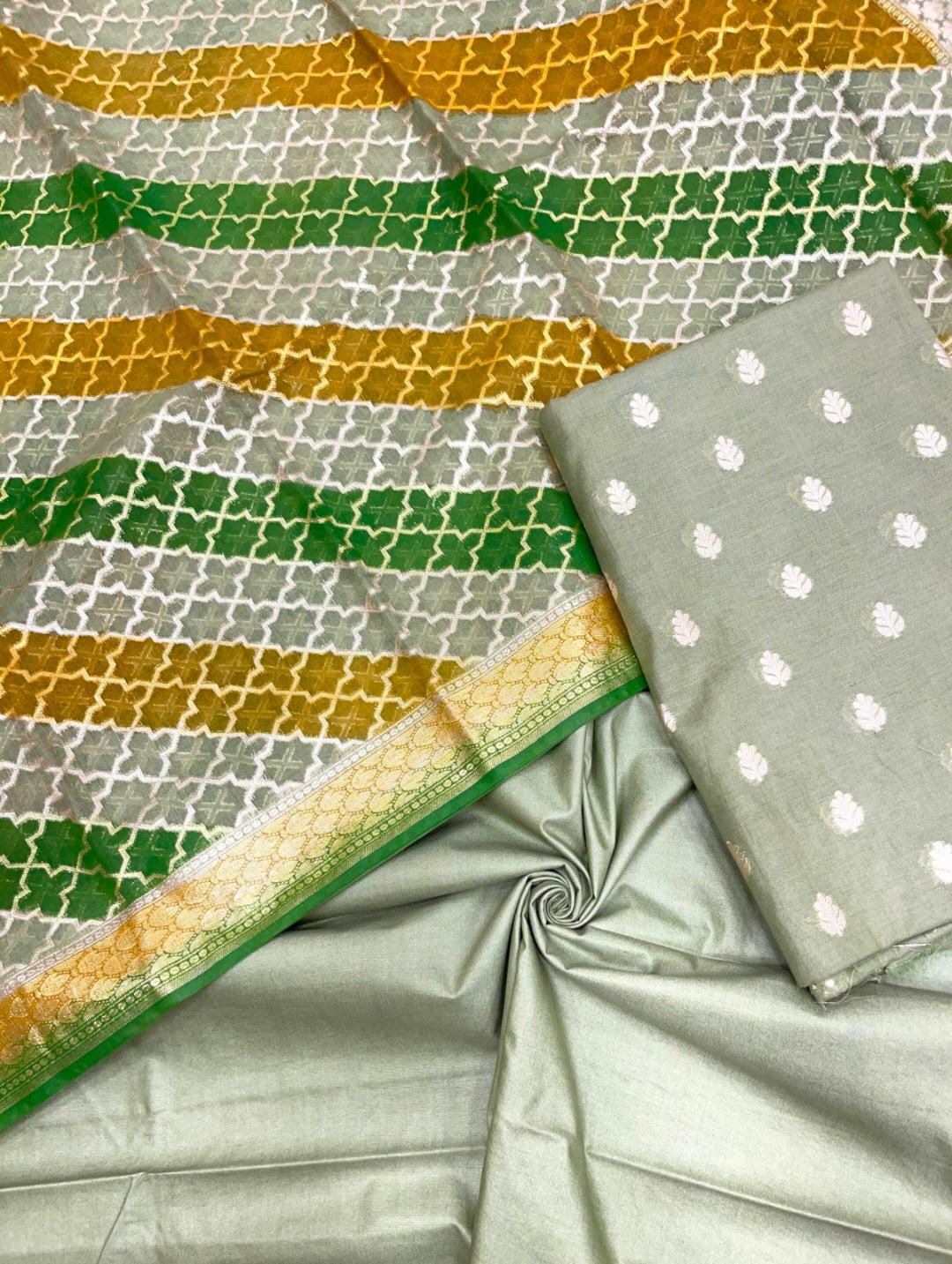 Gray fabric with green and gold patterns, including a folded piece with white floral patterns.
