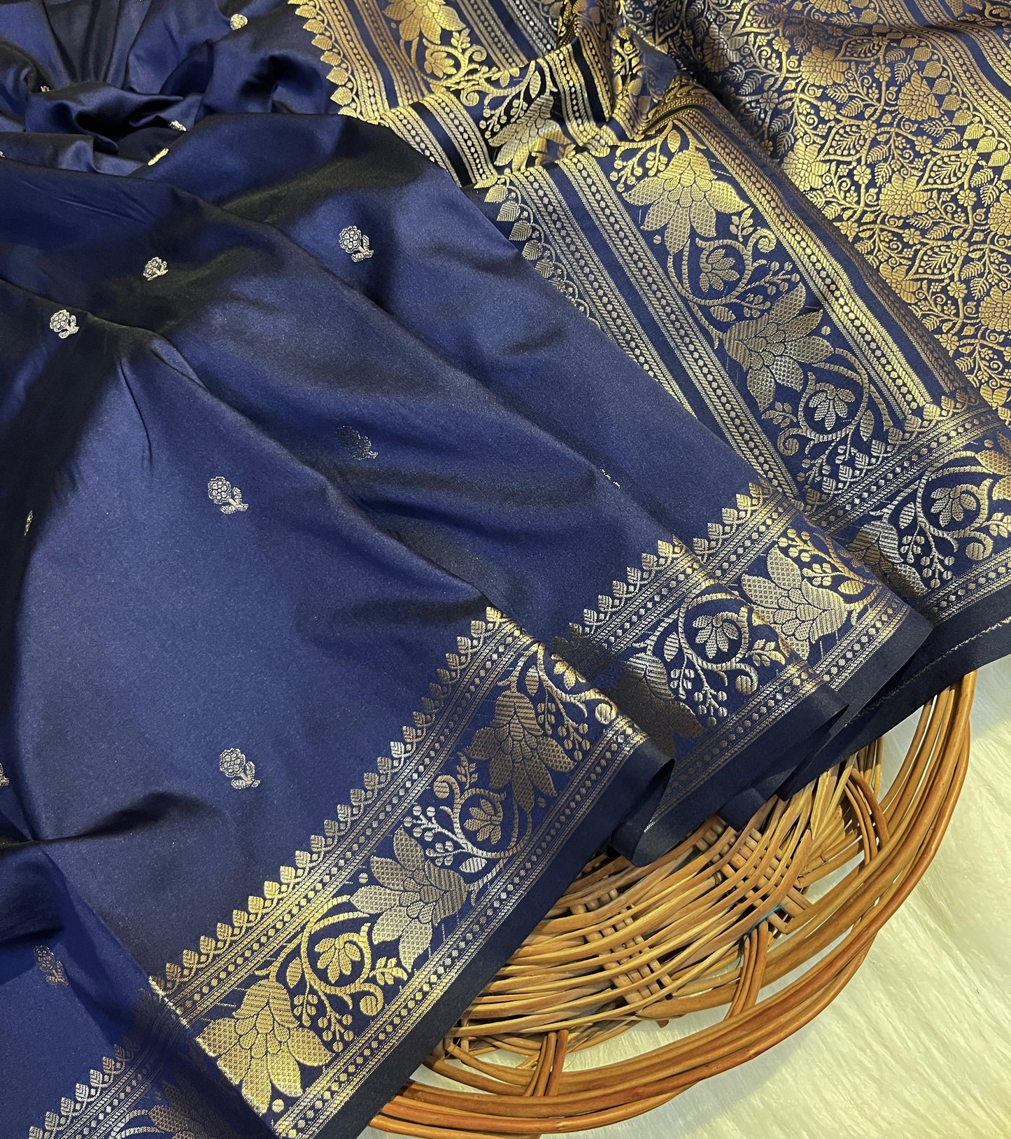 Blue saree with gold and white floral patterns on a woven basket