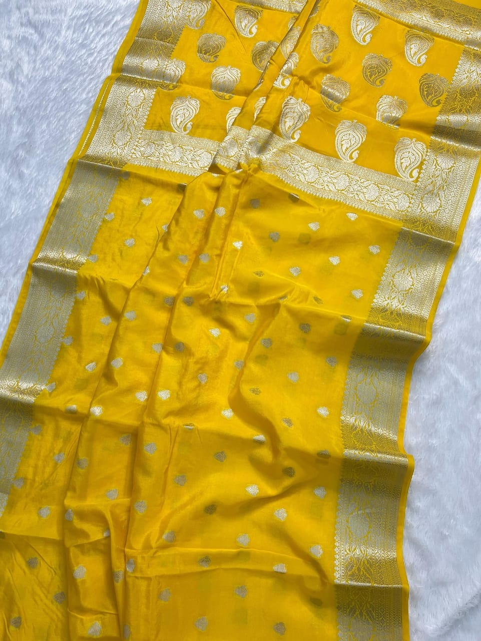 Yellow saree with gold border and patterns on a white background