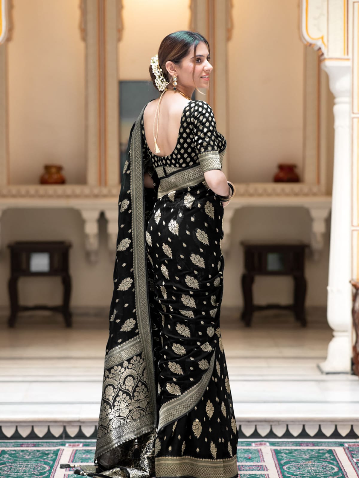 Woman in a black saree with white patterns in an elegant indoor setting