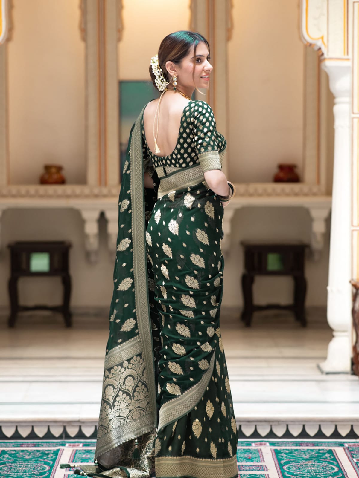 Woman in a green saree with a white pattern in an elegant indoor setting