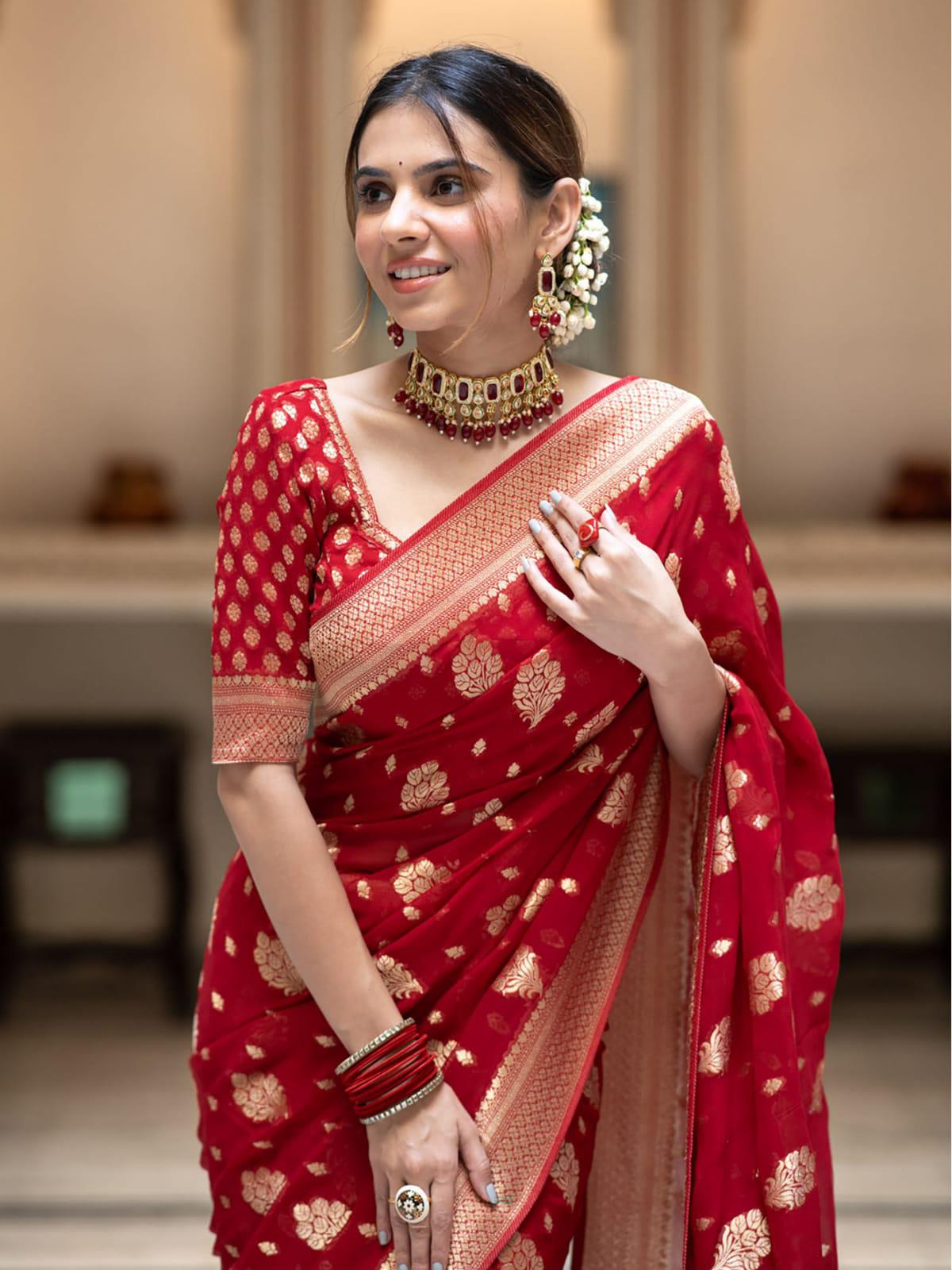 Woman wearing a red saree with gold patterns in an indoor setting