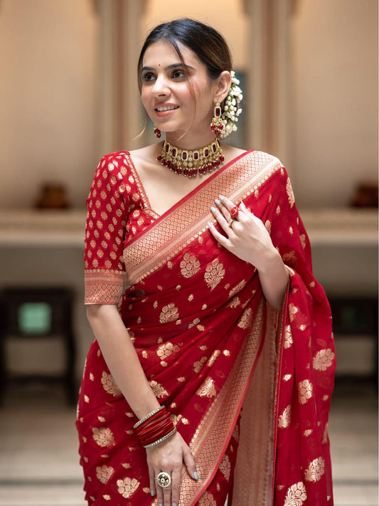 Woman wearing a red saree with gold patterns in an indoor setting