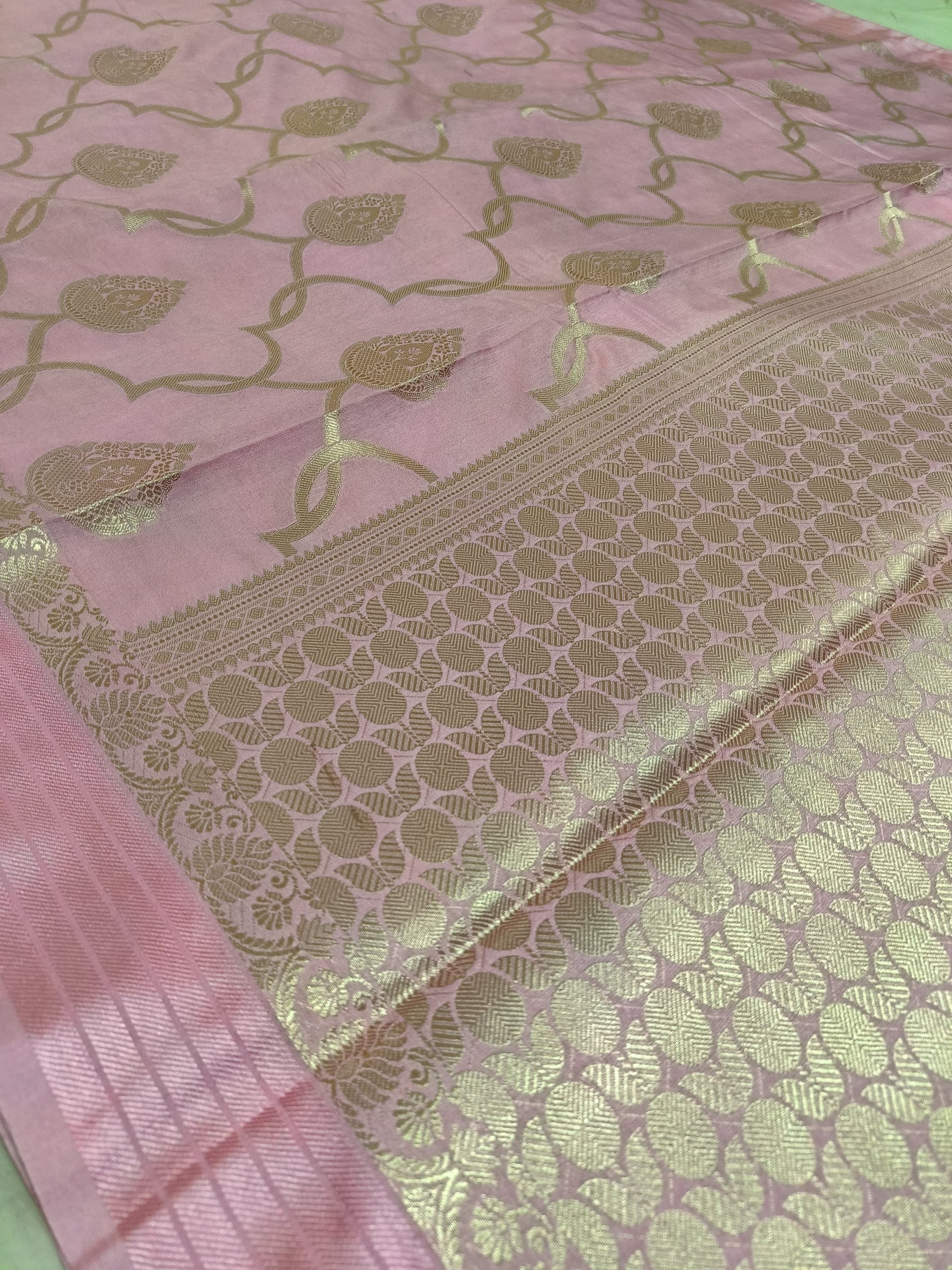 Pink fabric with gold leaf patterns on a green background