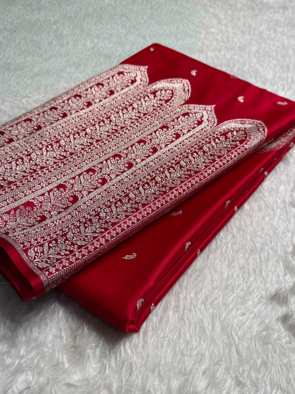 Red fabric with white intricate patterns on a textured gray background