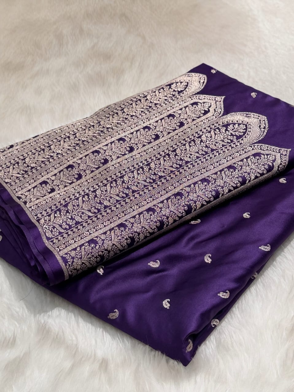 Purple fabric with intricate white embroidery on a light gray background