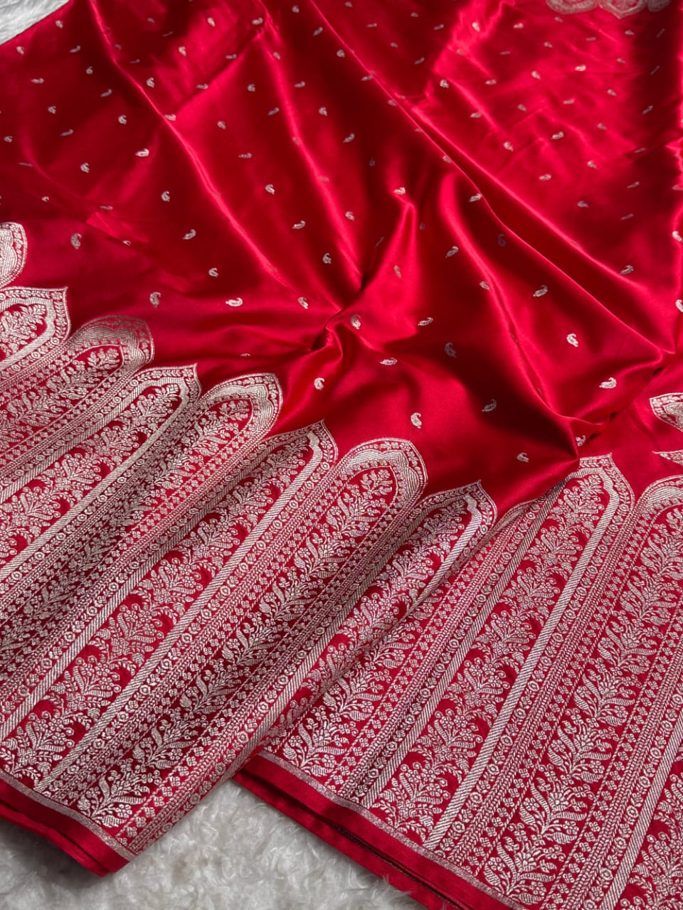 Red fabric with white intricate patterns on a textured surface