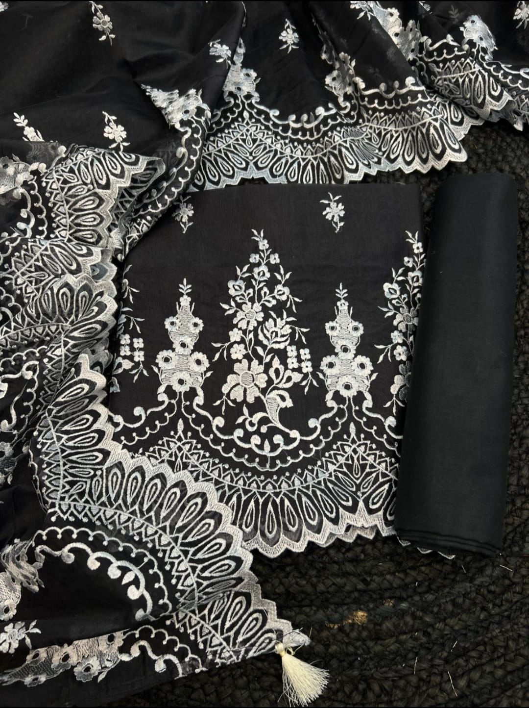 Black fabric with intricate white embroidery on a textured black background