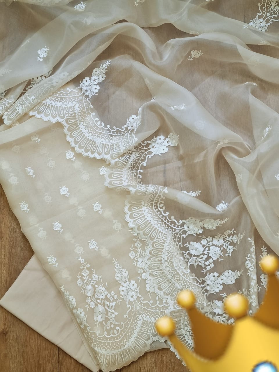 Beige fabric with white lace embroidery on a wooden surface