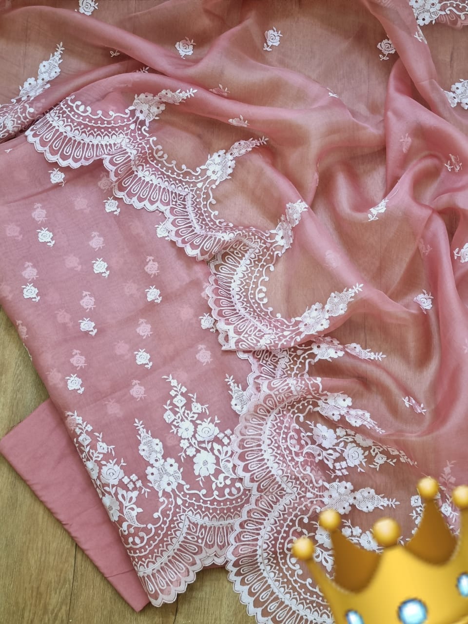 Pink fabric with white lace detailing on a wooden surface