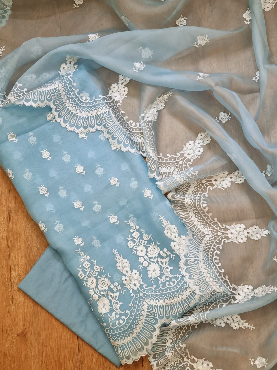 Light blue fabric with white lace detailing on a wooden surface