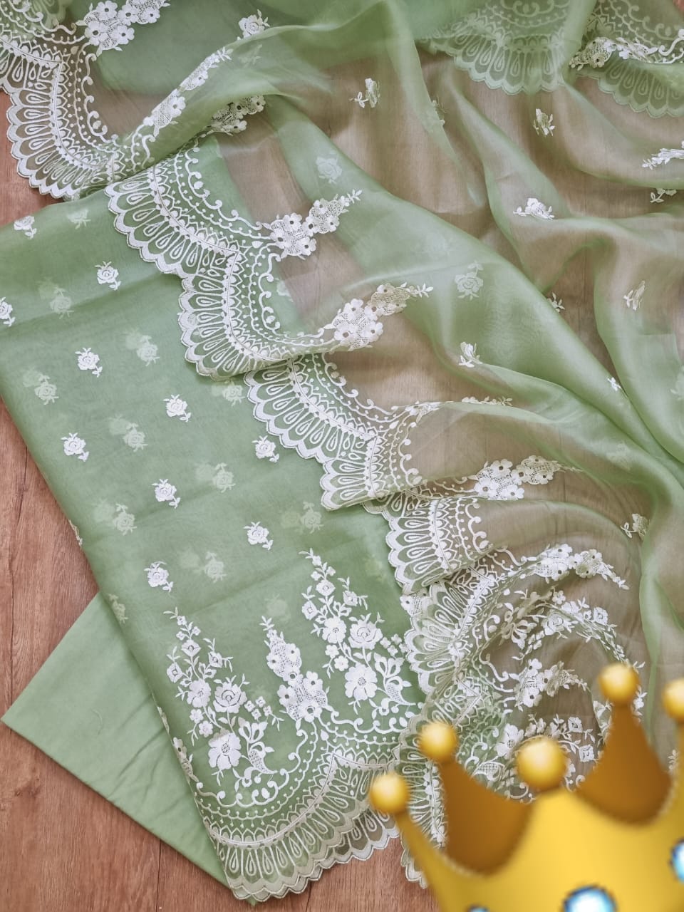 Green fabric with white lace embroidery on a wooden surface