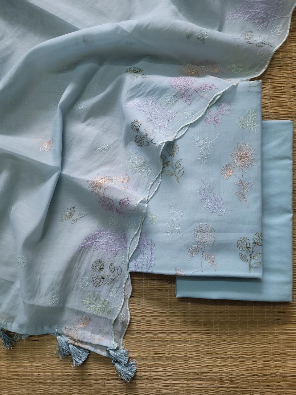 Light blue fabric with floral embroidery on a wooden surface