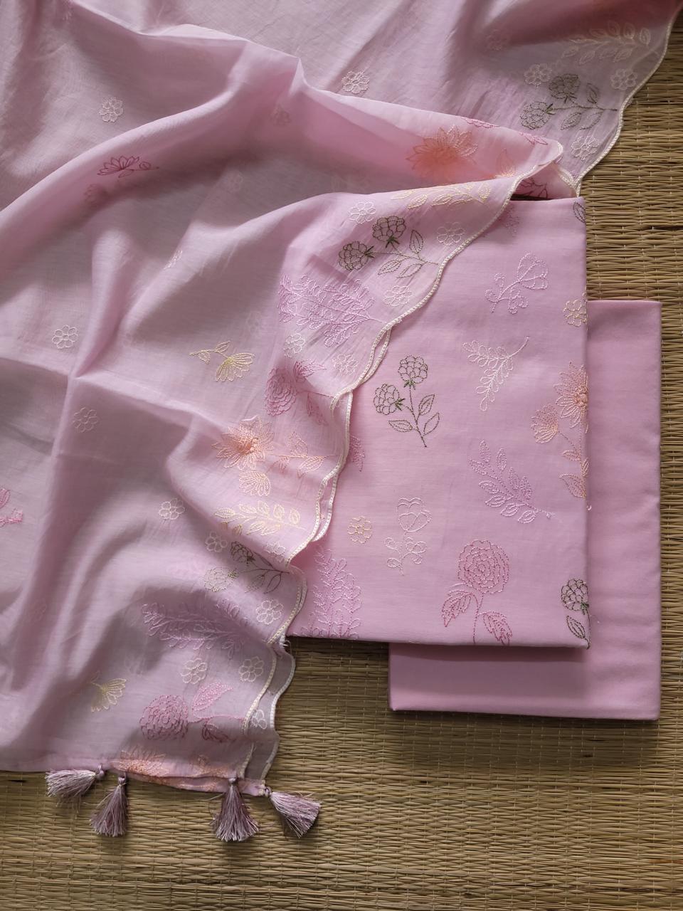 Pink fabric with floral embroidery on a wooden surface