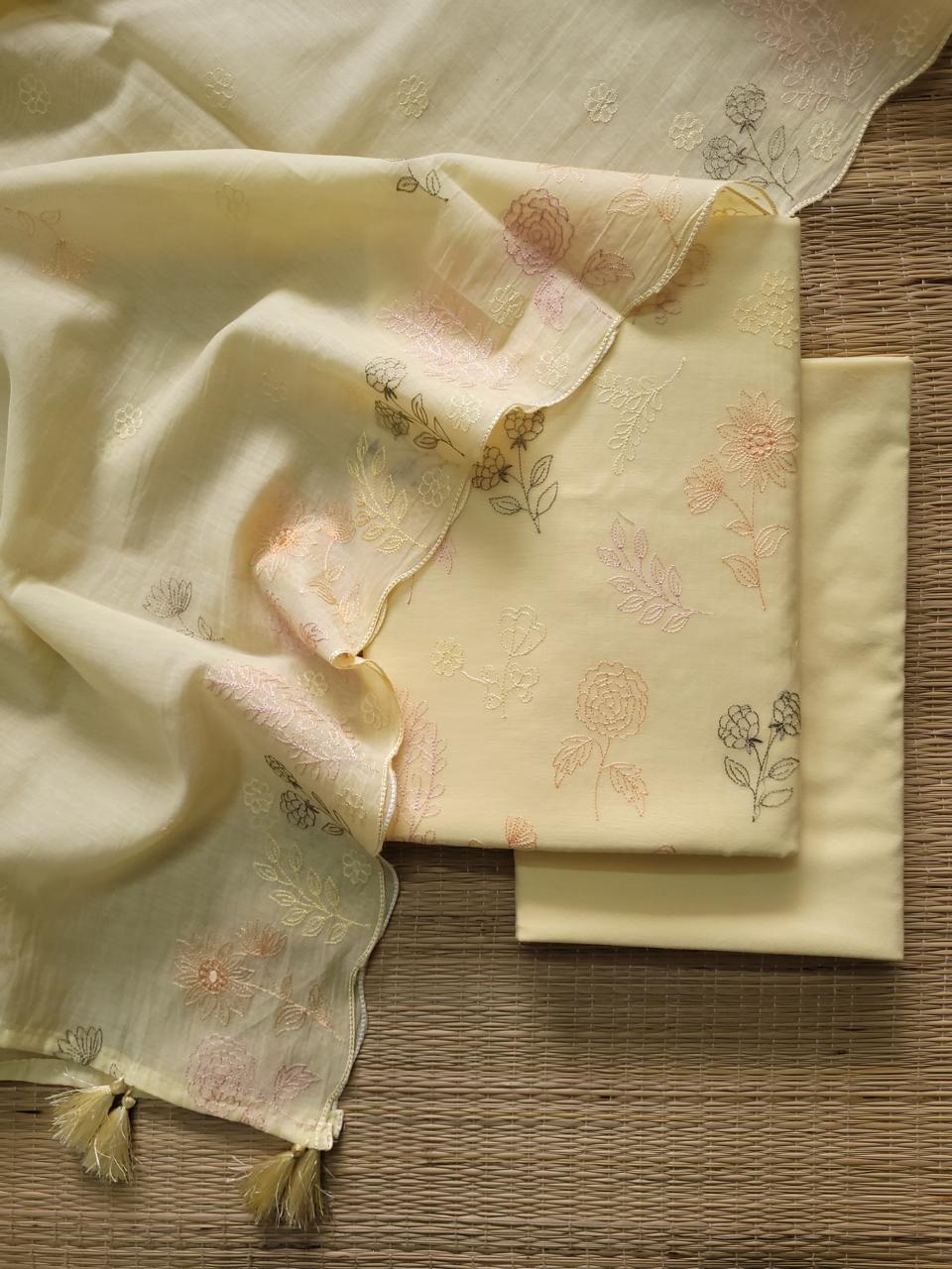 Light yellow fabric with floral embroidery on a wooden surface