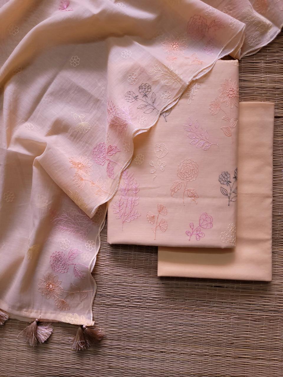 Light pink fabric with floral embroidery on a wooden surface