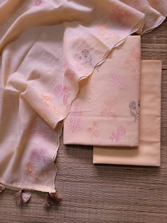 Light pink fabric with floral embroidery on a wooden surface