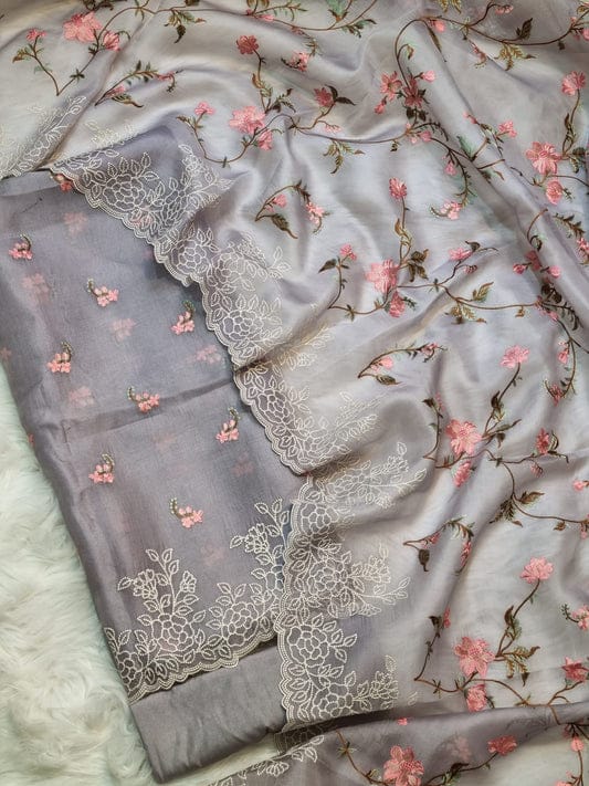 Gray fabric with floral embroidery and pink flowers on a textured surface