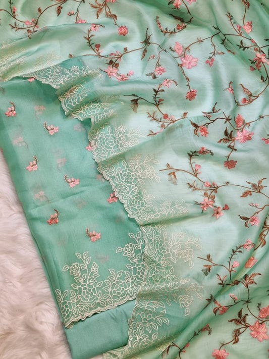 Light blue fabric with floral embroidery and pink flowers on a textured surface