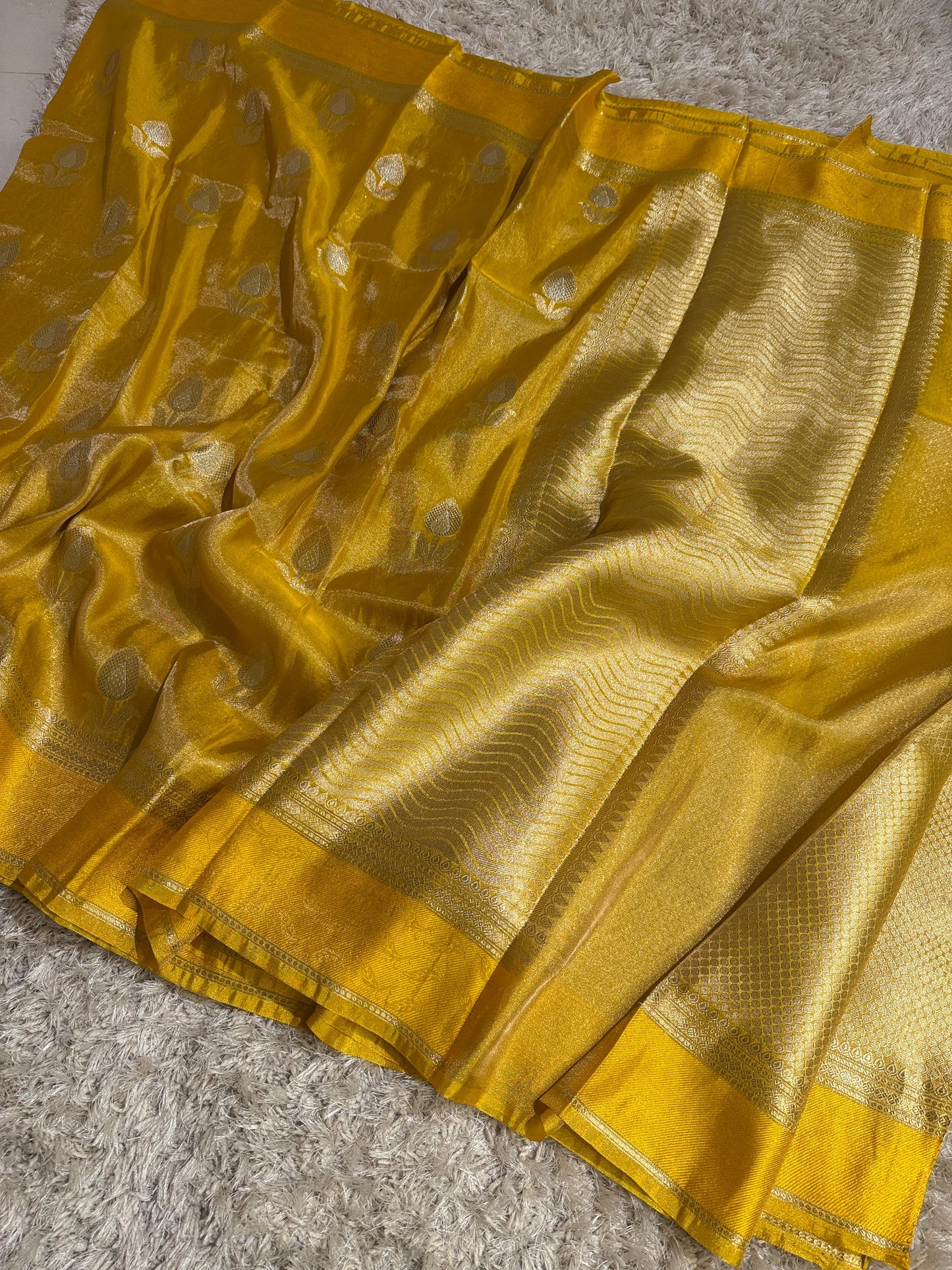 Yellow saree with intricate patterns on a textured surface