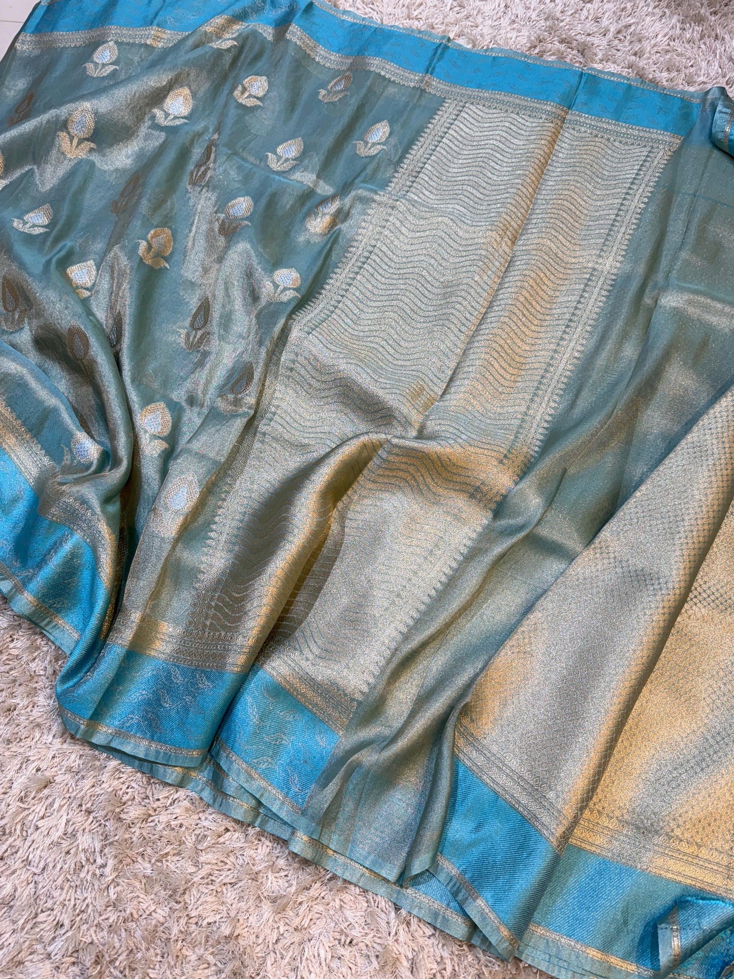 Blue and green saree with intricate patterns on a textured surface
