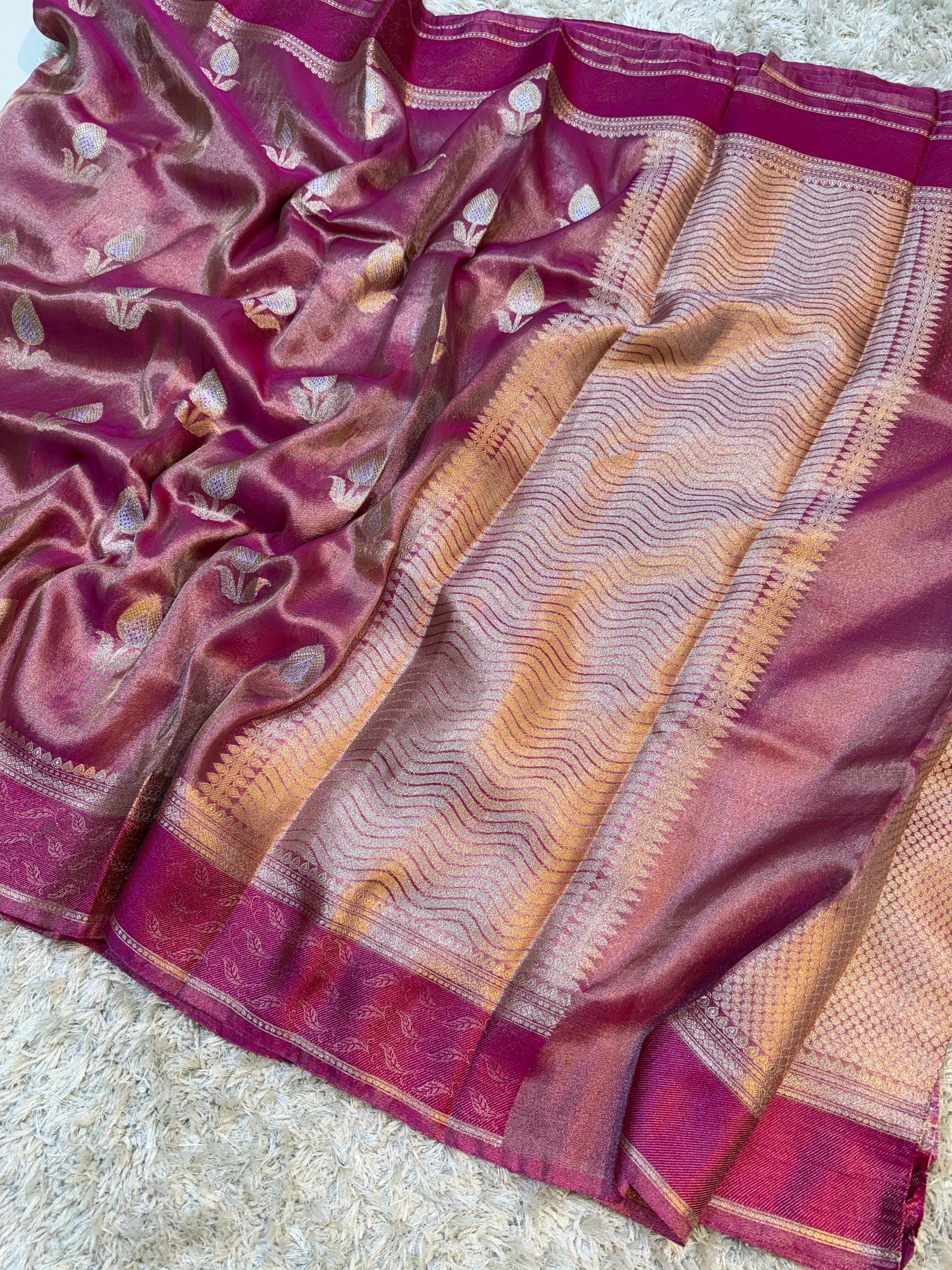 Close-up of a pink and gold saree with intricate patterns on a light background